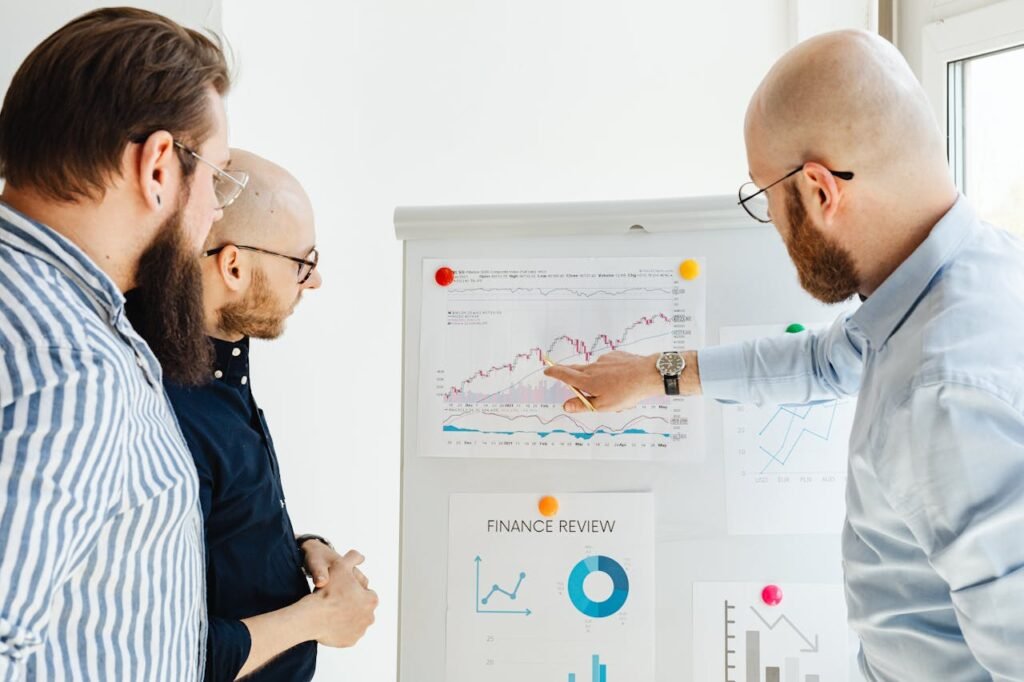 Three professionals analyzing financial charts and graphs on a presentation board, discussing strategic planning and performance metrics for marketing growth.