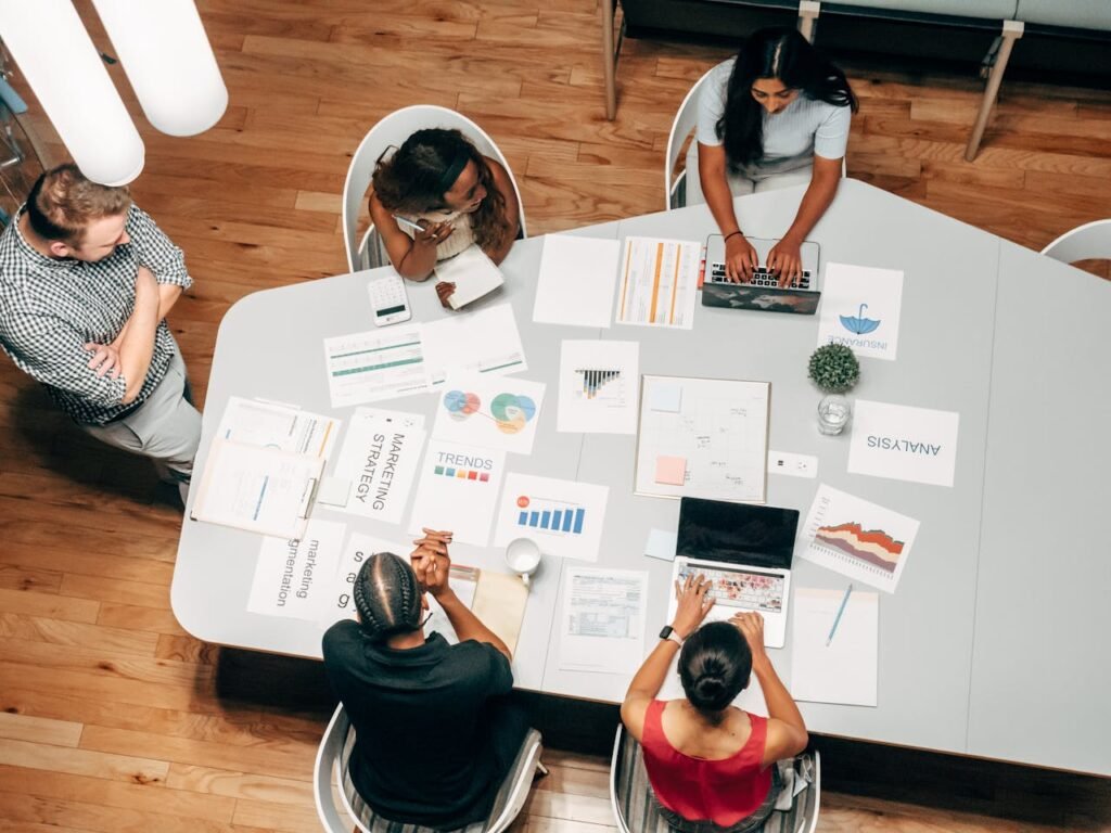 Group of professionals collaborating on marketing strategies at a conference table, surrounded by charts, graphs, and analysis documents, emphasizing tailored marketing solutions.