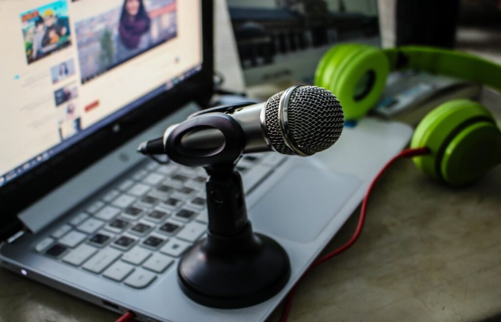 Microphone on a laptop keyboard with green headphones, representing content creation and digital communication strategies.